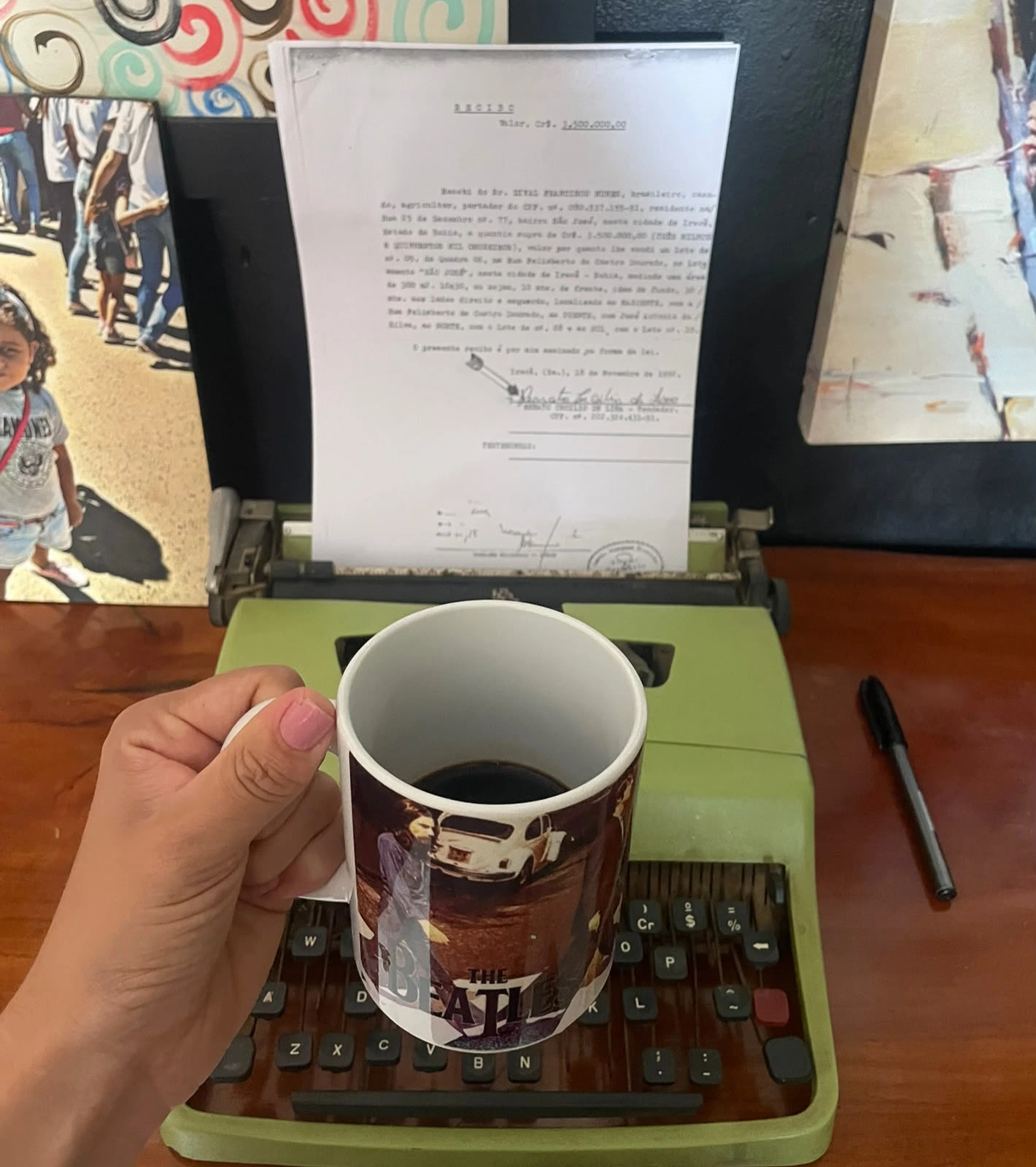 Uma pessoa segurando uma xícara de café de frente para uma máquina de escrever com um texto expresso